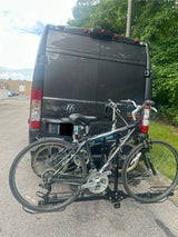 Rear view of a dark gray RV rental van, with two bicycles mounted on a rear hitch rack, ready for outdoor adventures.