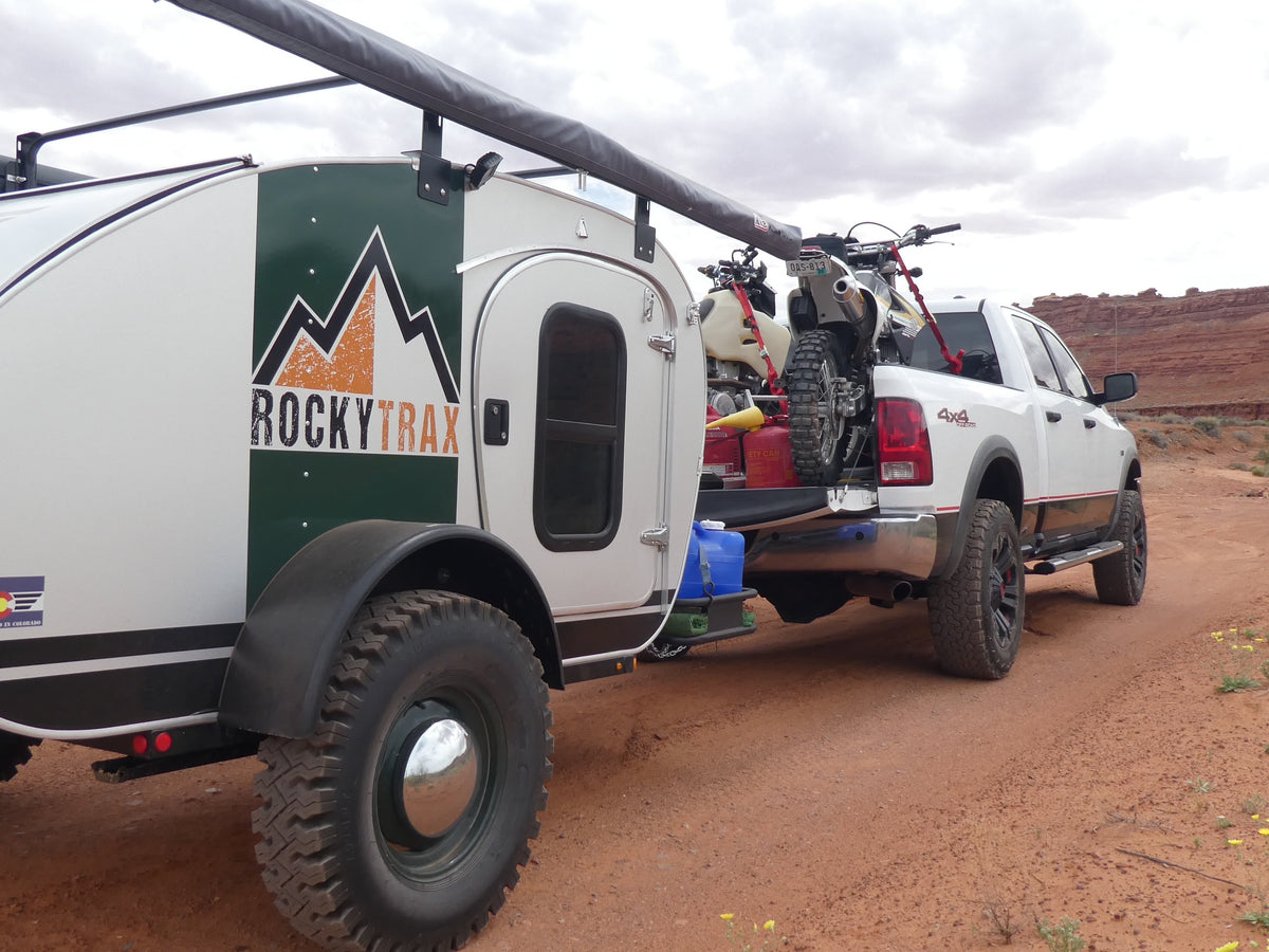 Adventure awaits! This RockyTrax off-road teardrop camper and dirt bikes are ready for exploration, perfect for an RV rental in red rock country.