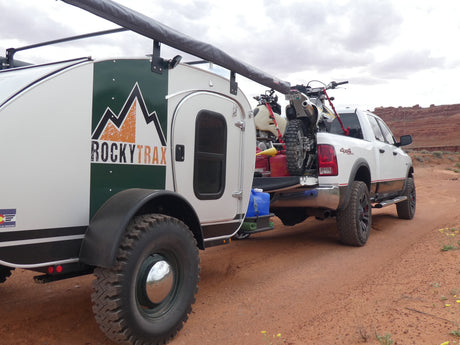 Adventure awaits! This RockyTrax off-road teardrop camper and dirt bikes are ready for exploration, perfect for an RV rental in red rock country.