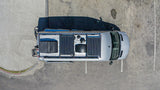 Aerial view of a silver camper van, equipped with roof solar panels. Parked on concrete, ideal for your next rv rental adventure.