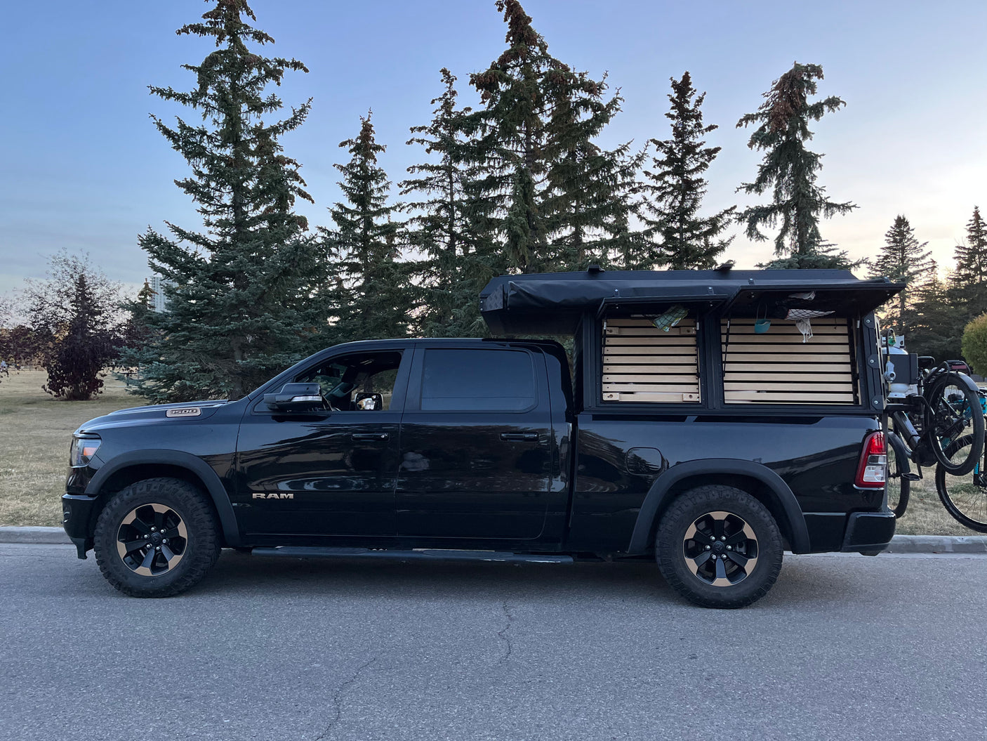 Black Ram truck with custom slat-sided camper and bike rack. Perfect rv rental for outdoor adventure.