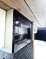 Stylish RV rental kitchen featuring a black microwave, honeycomb tile backsplash, and a modern wood plank ceiling.