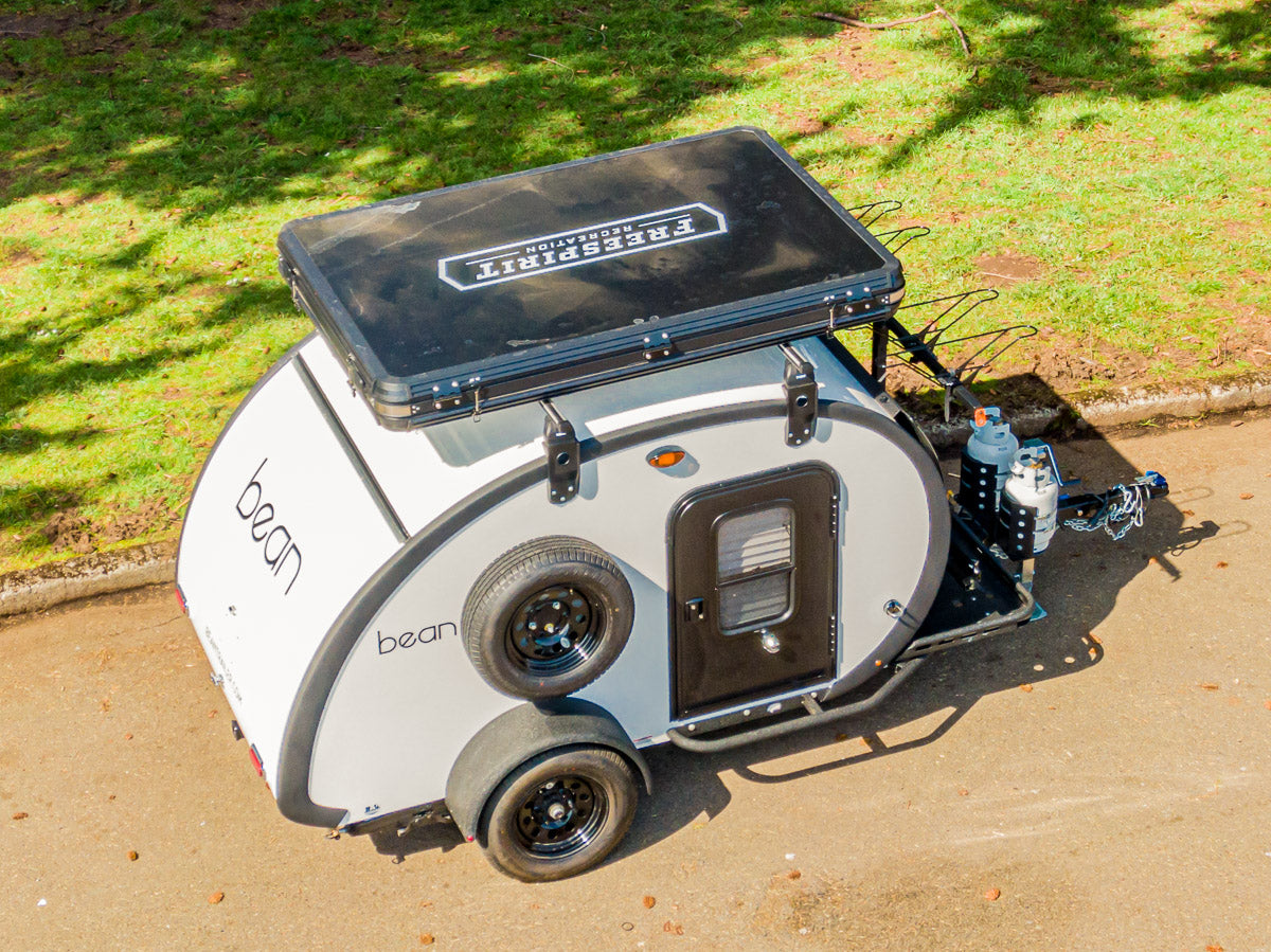 Overhead shot of a compact white Bean teardrop camper, featuring a rooftop tent, ideal for your next RV rental & camping trip.