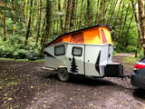 Taxa Cricket pop-up camper, an rv rental, parked at a lush, mossy forest campsite. Perfect for outdoor adventure.