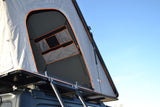 Grey rooftop tent open on vehicle roof, revealing orange trim & interior storage. Perfect for RV rental adventure.