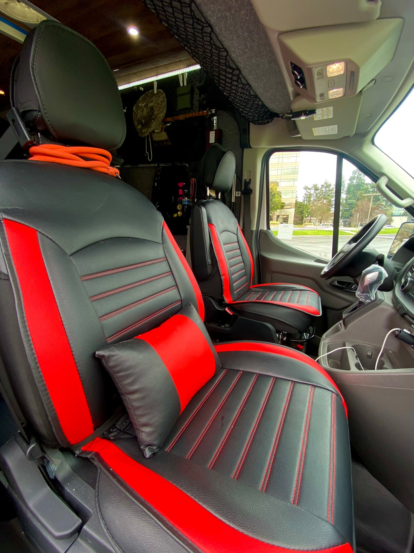 Step into this RV rental! Features custom black & red seats, offering a comfortable camper van interior view.