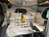 Cozy RV rental interior featuring a 'Destination Camping' bed, laptop table, and integrated amenities.