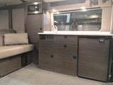 Explore our RV rental's versatile interior: a well-equipped camper kitchen with microwave, fridge, & comfy seating area.