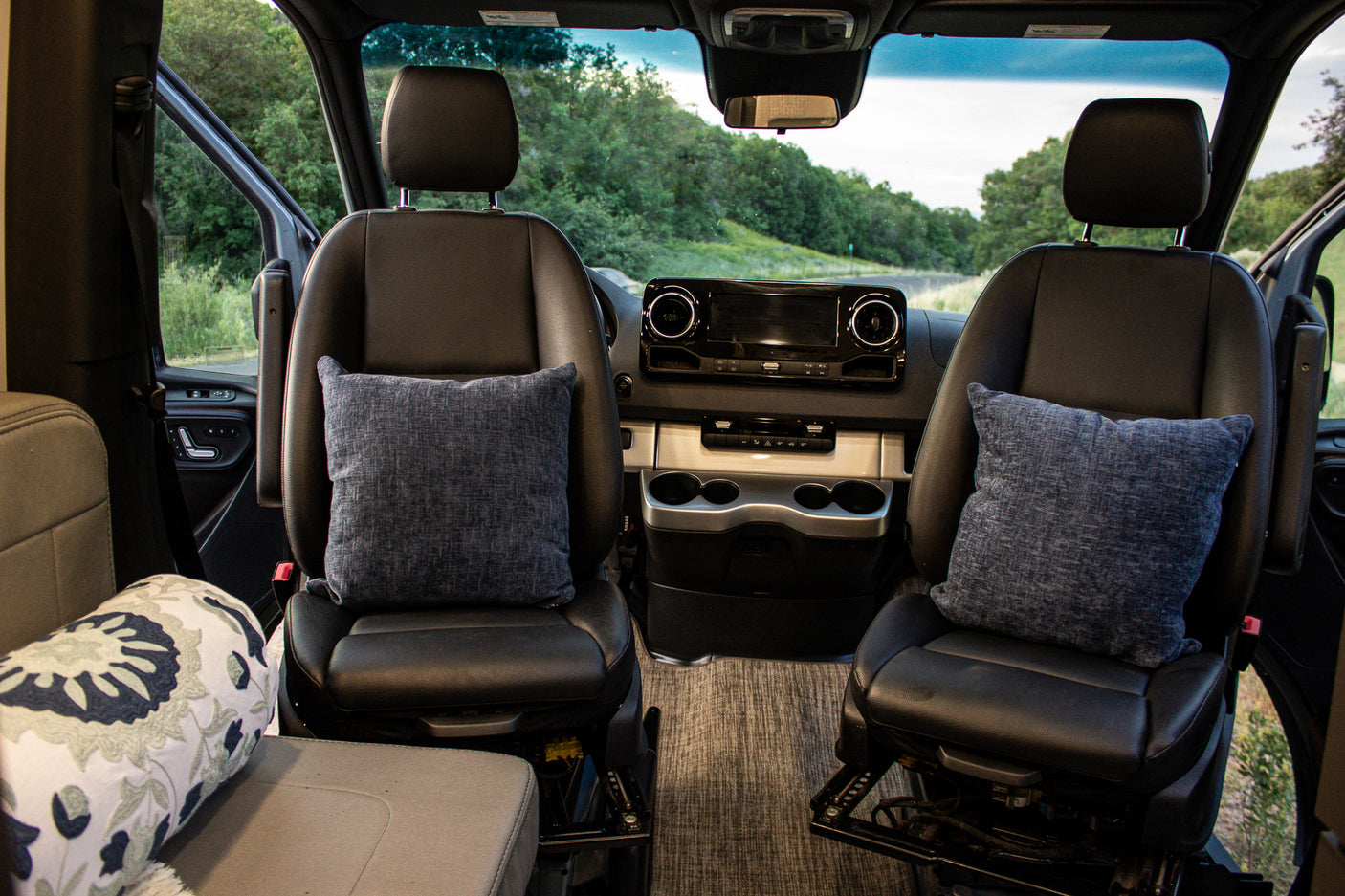 View from inside this spacious RV rental, highlighting the comfortable front seats, dashboard, and scenic outdoors.