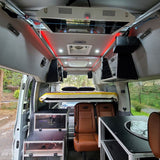 Modern RV rental van interior showcasing an elevated bed, modular storage, and seating. Ready for your next adventure!