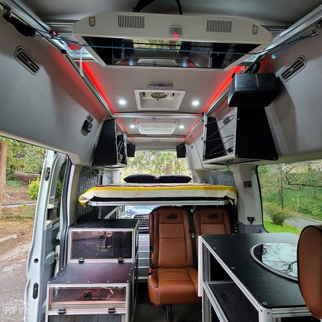 Modern RV rental van interior showcasing an elevated bed, modular storage, and seating. Ready for your next adventure!
