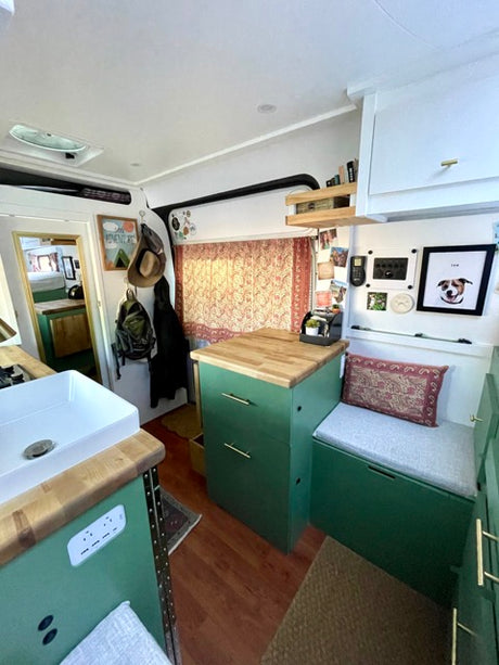Cozy RV rental interior with green cabinets, wooden counters, and a comfy bench seat. Perfect mobile home setup.