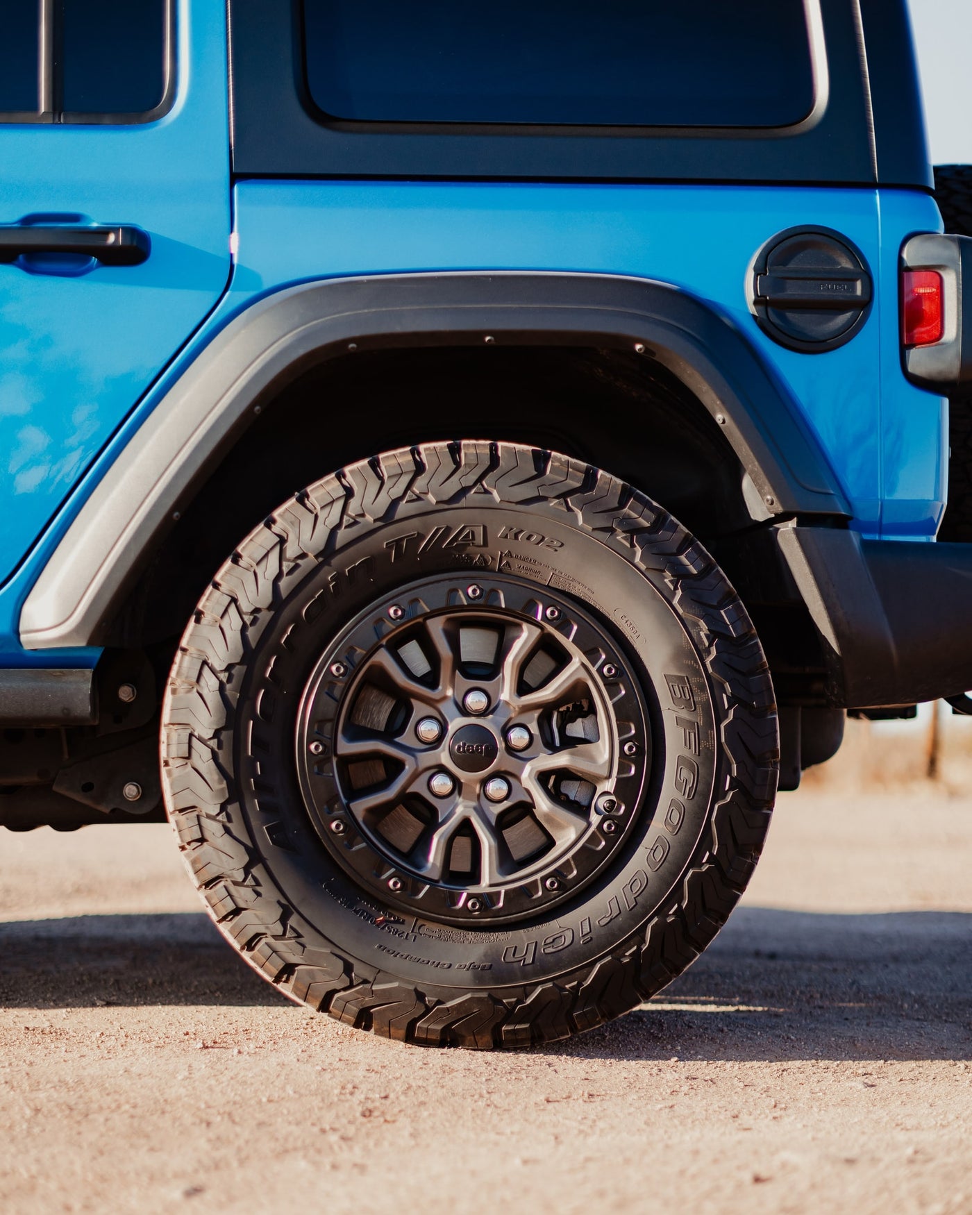 Side view of a blue Jeep Wrangler, highlighting its rugged BFGoodrich off-road tire and wheel. Great for any adventure or rv rental trip. — photo 2