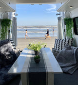 Beachfront RV rental offers a perfect view! Relax inside with plants & pillows while watching people walk the shore.