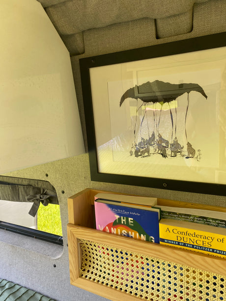 Cozy RV rental interior with framed wolf art, a wooden book nook displaying "The Vanishing Half" and "A Confederacy of Dunces."