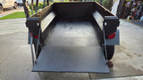 Robust overland trailer with tailgate lowered, showcasing its empty cargo bed. Ideal for hauling gear on an RV rental trip.
