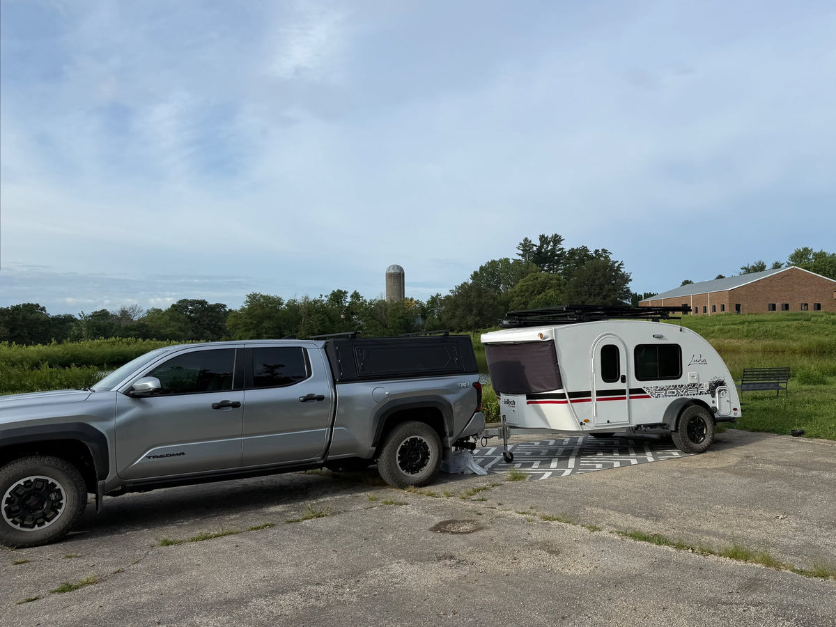  tree-filled campsite under a clear blue sky.|Silver pickup truck towing an RV rental teardrop trailer by a pond and silo — photo 3