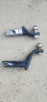 Trailer hitch ball mounts on concrete, essential for RV rental towing. Top has a label; bottom includes a pin.