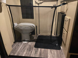 RV rental bathroom showing a toilet blocked by a black mesh pet gate on wood-look floors. Ideal for keeping pets out.