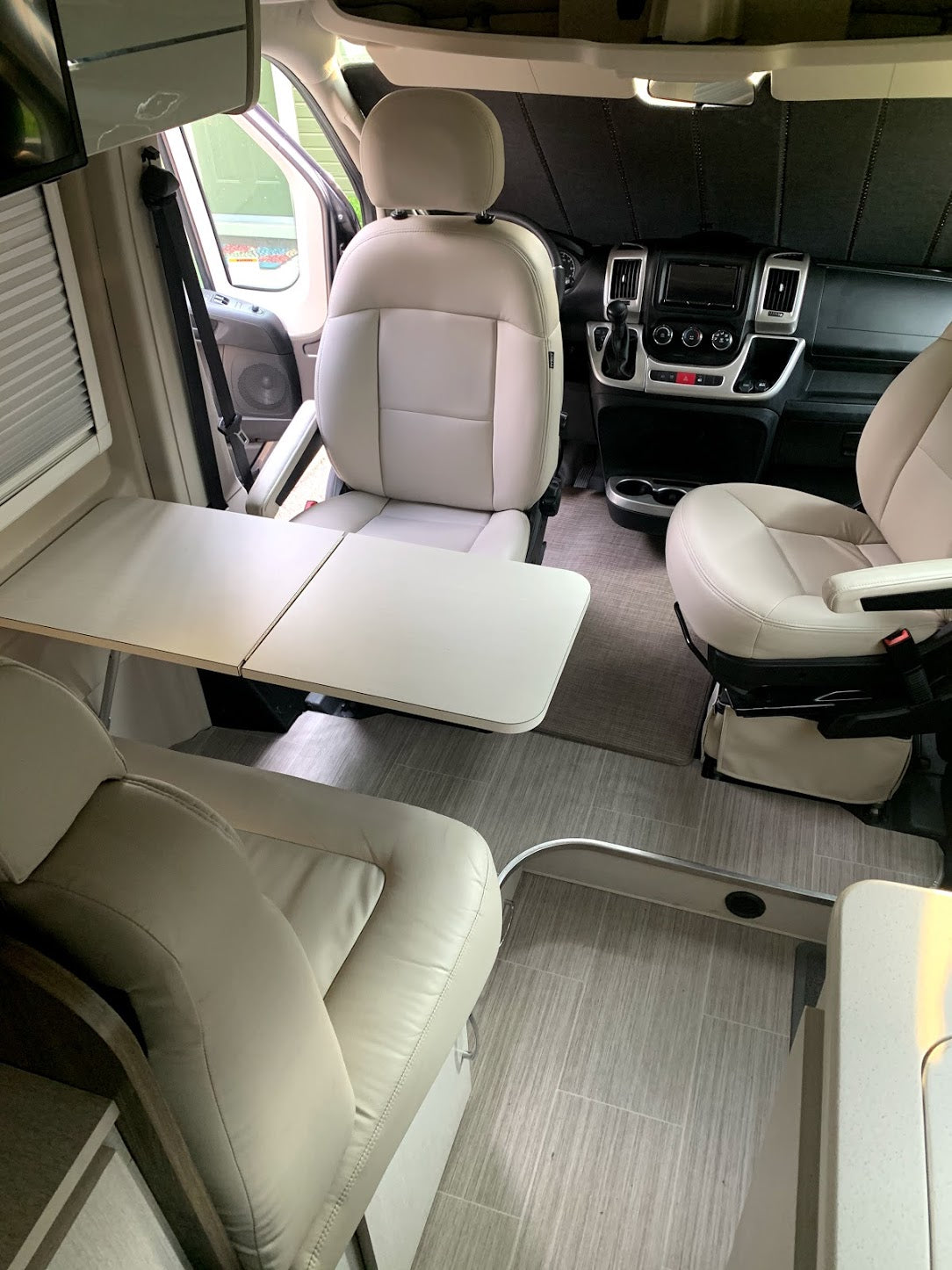 Spacious RV rental interior with swivel seats and a foldable table, ideal for comfortable travel and dining on the road.