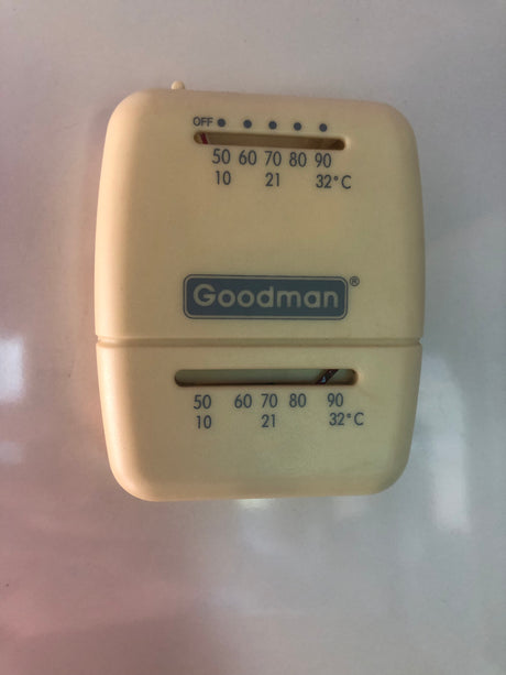 This Goodman analog thermostat in an RV rental controls temperature, showing Fahrenheit and Celsius settings for climate control.