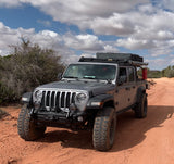 Off-road ready silver Jeep Gladiator with rooftop tent on a desert path. Perfect for an RV rental adventure.