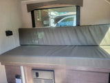 RV rental interior: Cushioned dinette, window view, USB charging, and electrical panel below.