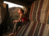 Man in a cozy camper van rental, gazing at serene sunset hills. Perfect RV travel escape.