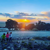 Three kids gaze at a stunning sunset over a vast landscape. An RV rental adventure offers breathtaking views like this!