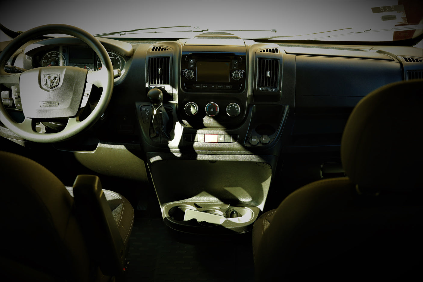 Inside a Ram **rv rental**: Driver's view of the dashboard, featuring steering wheel, infotainment display, gear shifter, and climate controls.