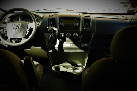 Inside a Ram **rv rental**: Driver's view of the dashboard, featuring steering wheel, infotainment display, gear shifter, and climate controls.
