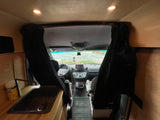 This cozy rv rental interior features a functional sink, front cockpit, and a stunning ocean view through the camper van windshield.