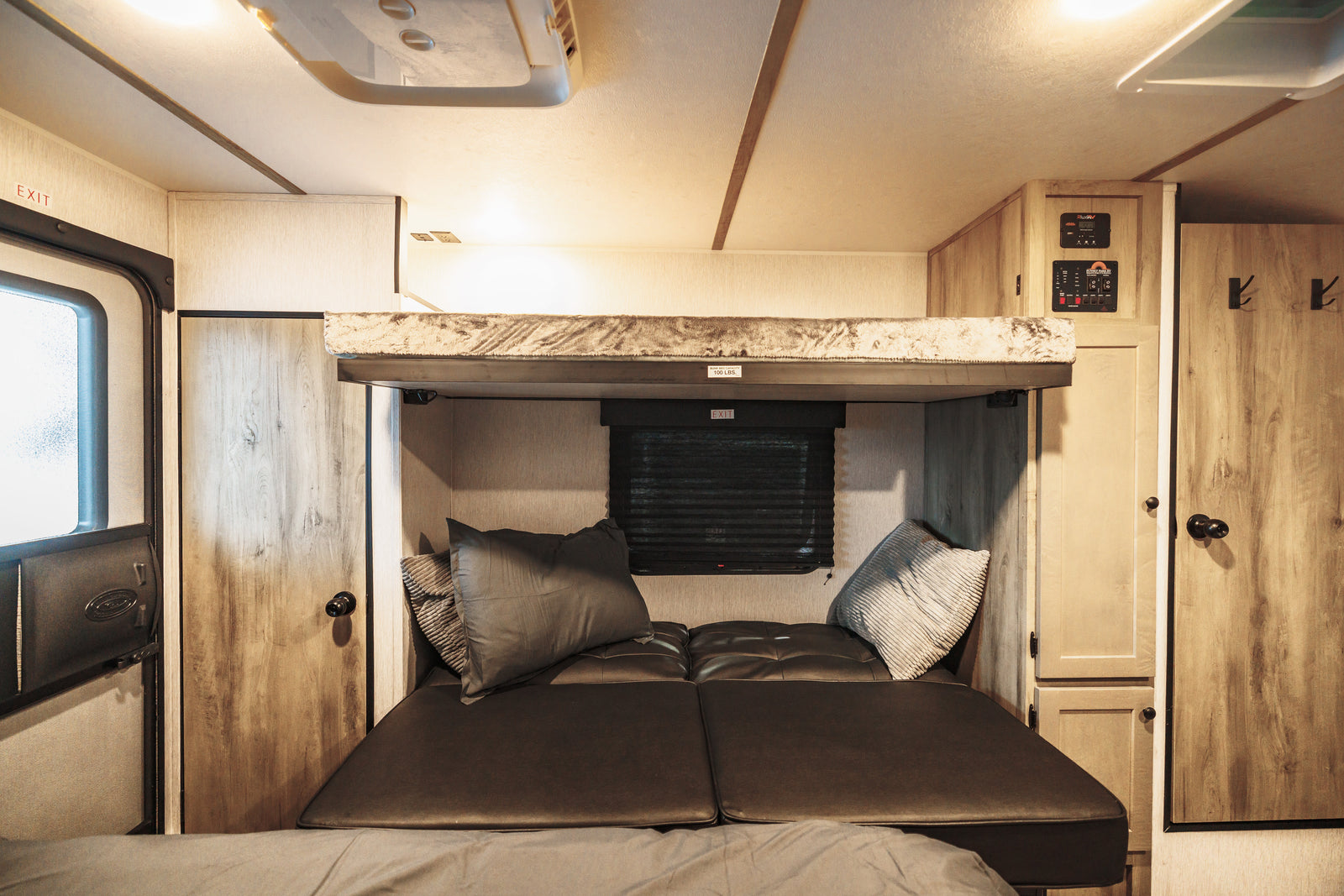Cozy RV rental interior featuring a lower bed/sofa and an upper bunk bed, ideal for a comfortable stay.
