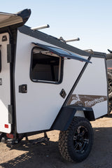This white TigerMoth overland RV rental features an open window, rugged tire, and black accents, ready for adventure.