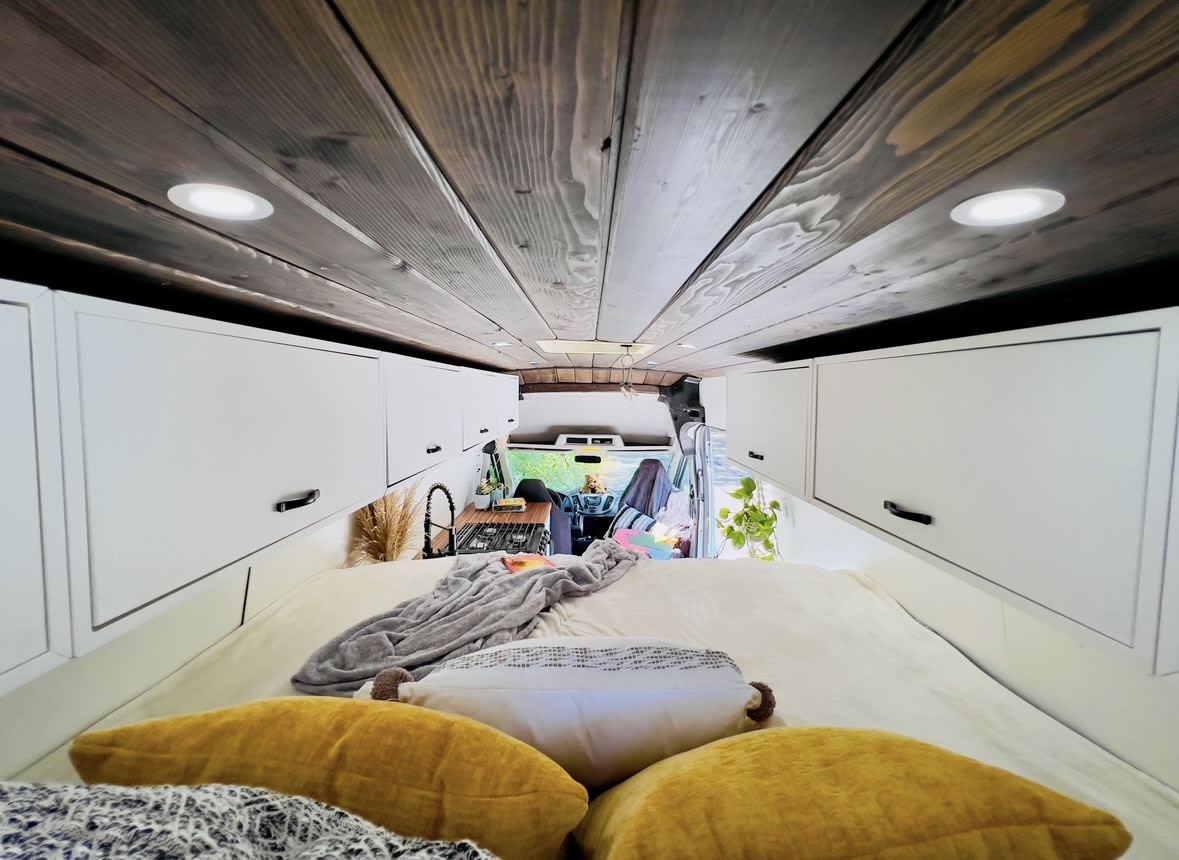  and cozy sleeping area.|Rear view of an RV rental: a white conversion van with open doors showing an elevated bed — photo 8
