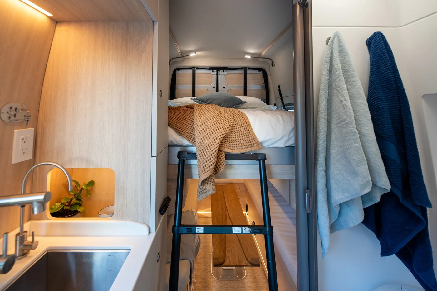  and comfortable sleeping area amidst nature.|Modern rv rental interior features a compact kitchen with a sink — photo 11