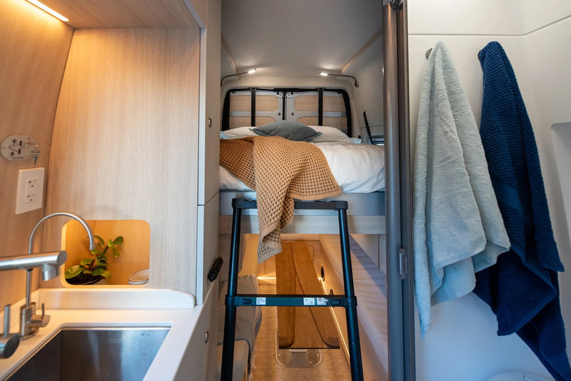  and comfortable sleeping area amidst nature.|Modern rv rental interior features a compact kitchen with a sink — photo 11