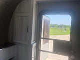 RV rental interior with open door revealing a scenic view. Cabinets and fire extinguisher visible.