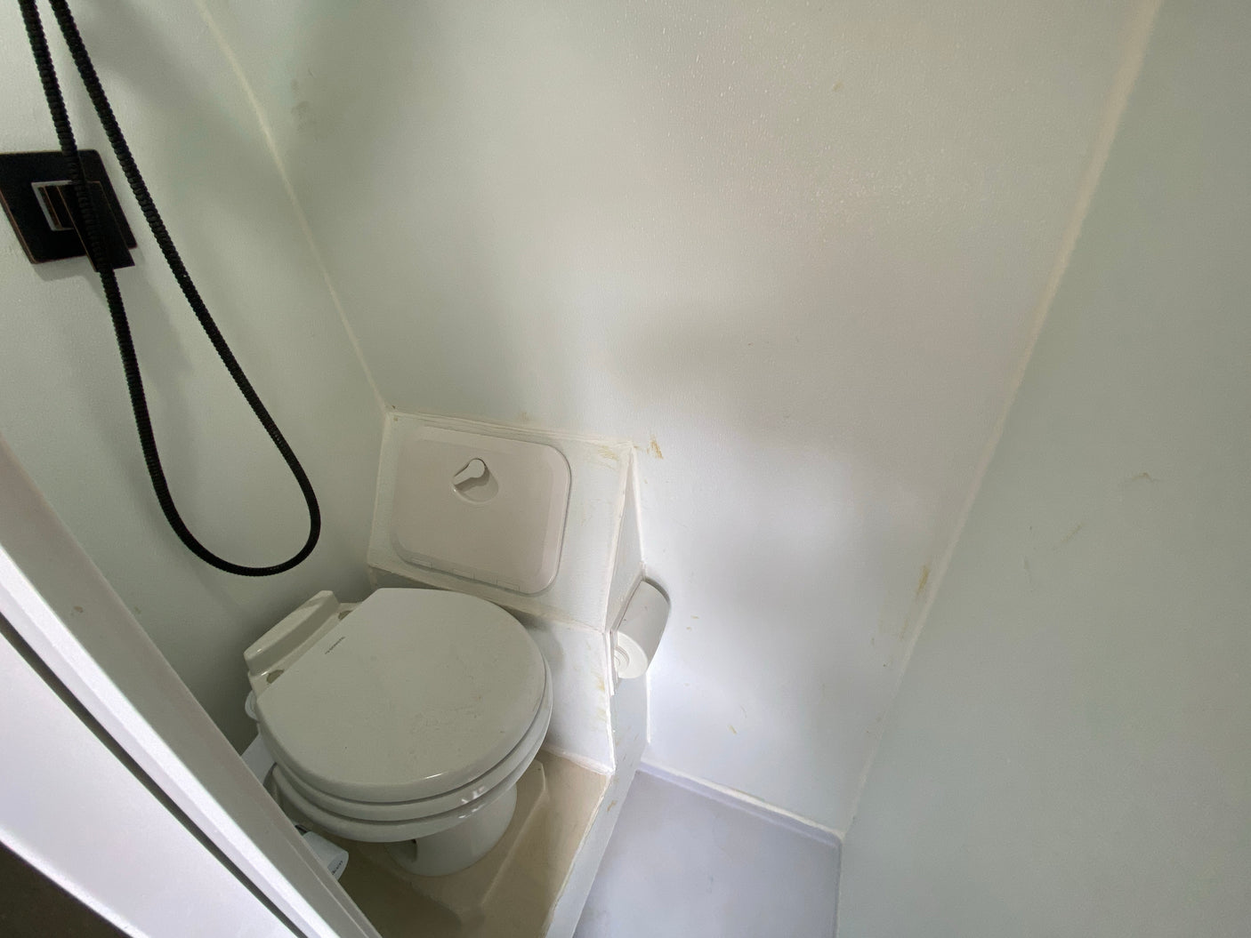 This RV rental features a compact, functional bathroom with a white toilet and shower, showing signs of use.