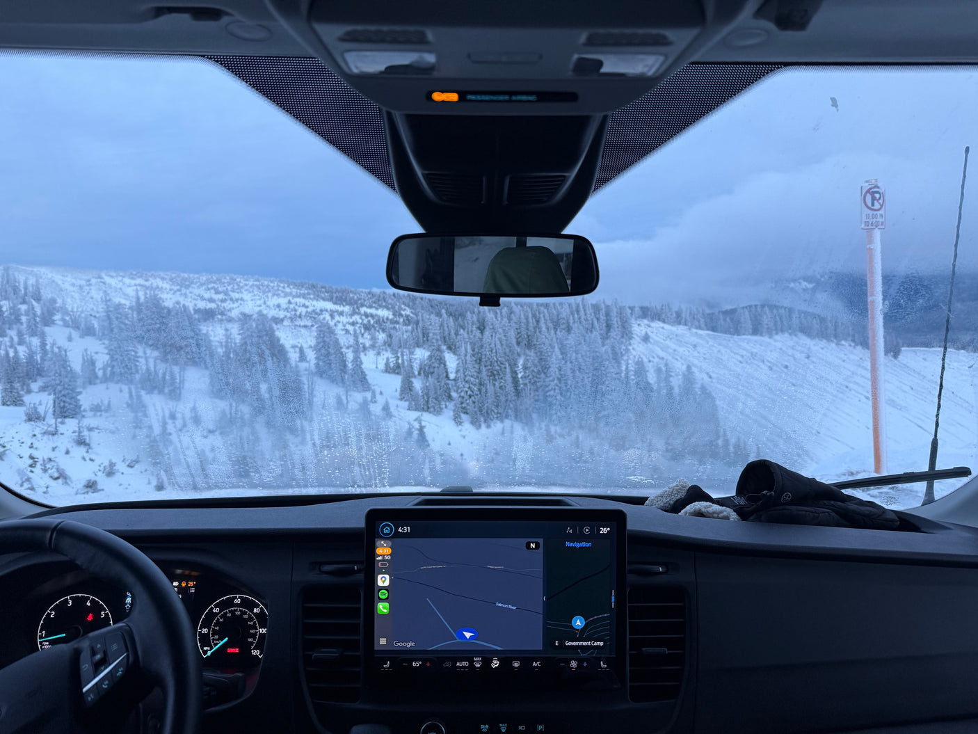 Snowy mountain view from an RV rental's dashboard, with navigation set to Government Camp. A winter road trip adventure.
