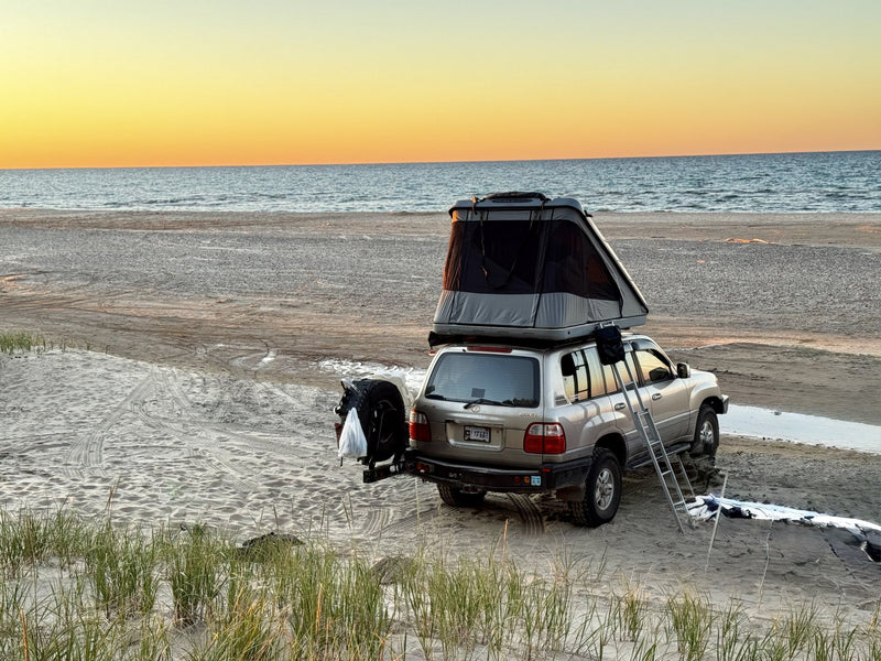 James Baroud Discovery Xtreme XXL rooftop tent fully deployed on a Toyota Land Cruiser parked on a Lake Michigan beach at sunset, ladder down — photo 1