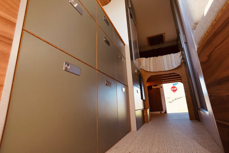 Spacious RV rental interior featuring modern storage, a cozy bed, and an open rear revealing an outdoor stop sign.