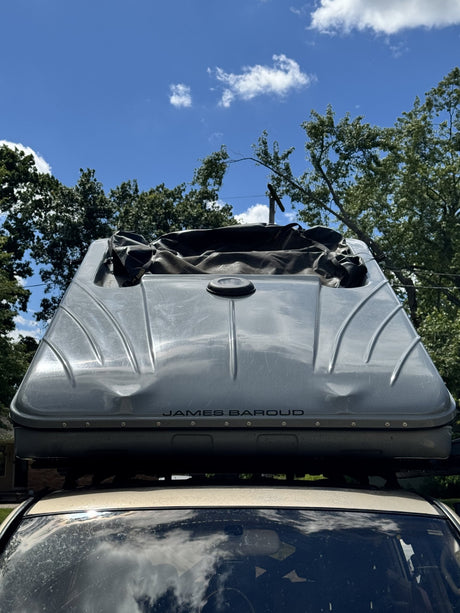 Rear view of the James Baroud shell with the lid raised, showing the roof-mounted exhaust fan port and the tent fabric folded inside