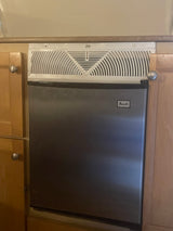 Compact Avanti mini-fridge/ice maker for RV rental kitchenette, built into light wood cabinetry with knobs.