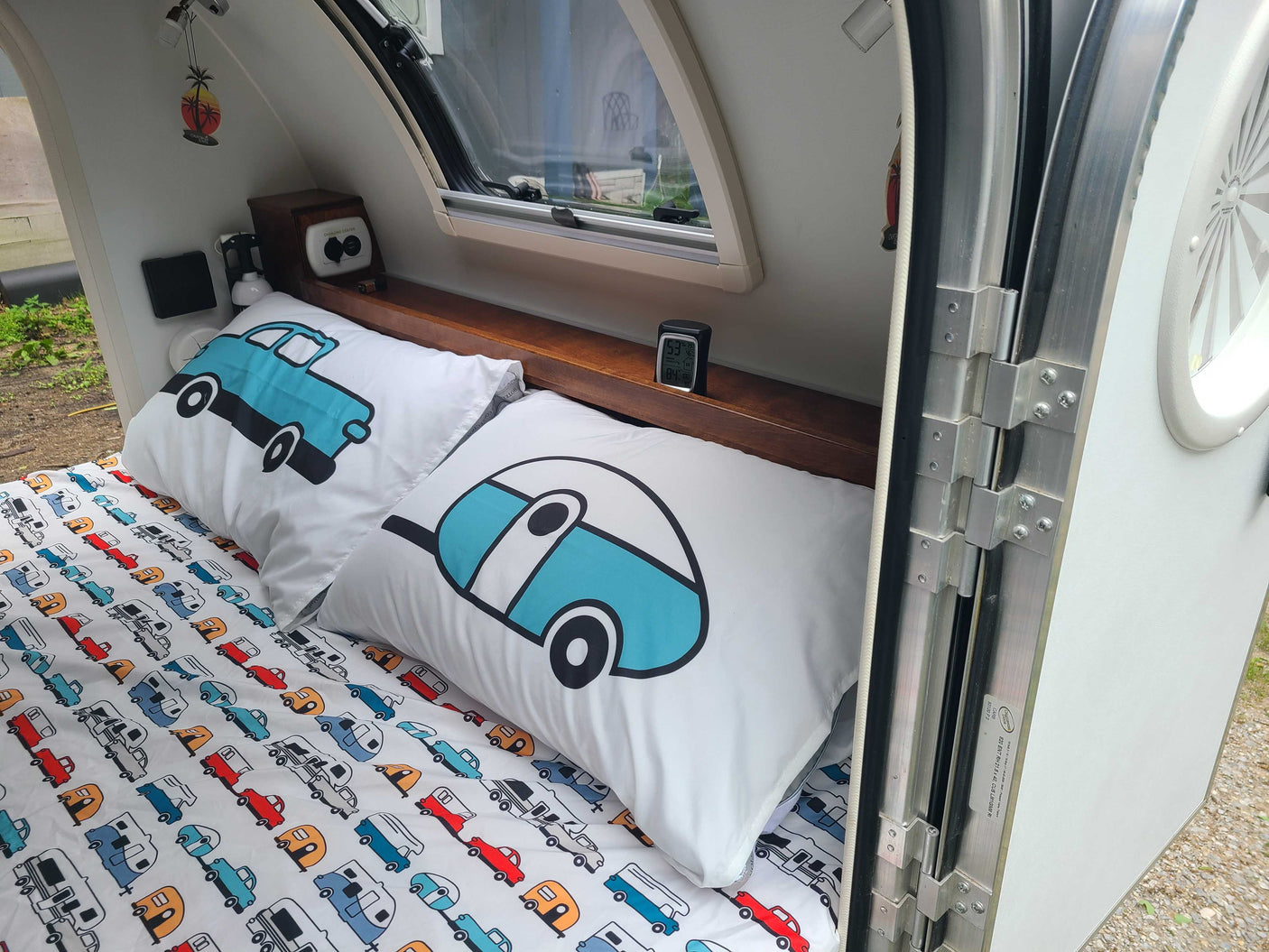 Cozy RV rental interior with fun car & camper bedding, charging center, and window view. Perfect for travel.