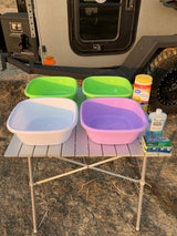 Portable wash station for RV rental camping, with colorful basins, wipes, and soap on a table outdoors.