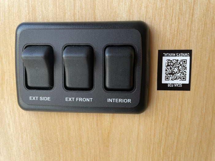 RV rental controls: switches for exterior side, front, and interior lights. Scan QR for owner's manual.