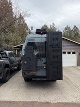RV rental: Heavily modified gray Sprinter camper van with robust rear racks, ideal for van life adventures & overlanding.