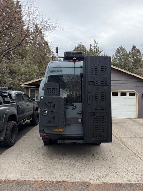 RV rental: Heavily modified gray Sprinter camper van with robust rear racks, ideal for van life adventures & overlanding.