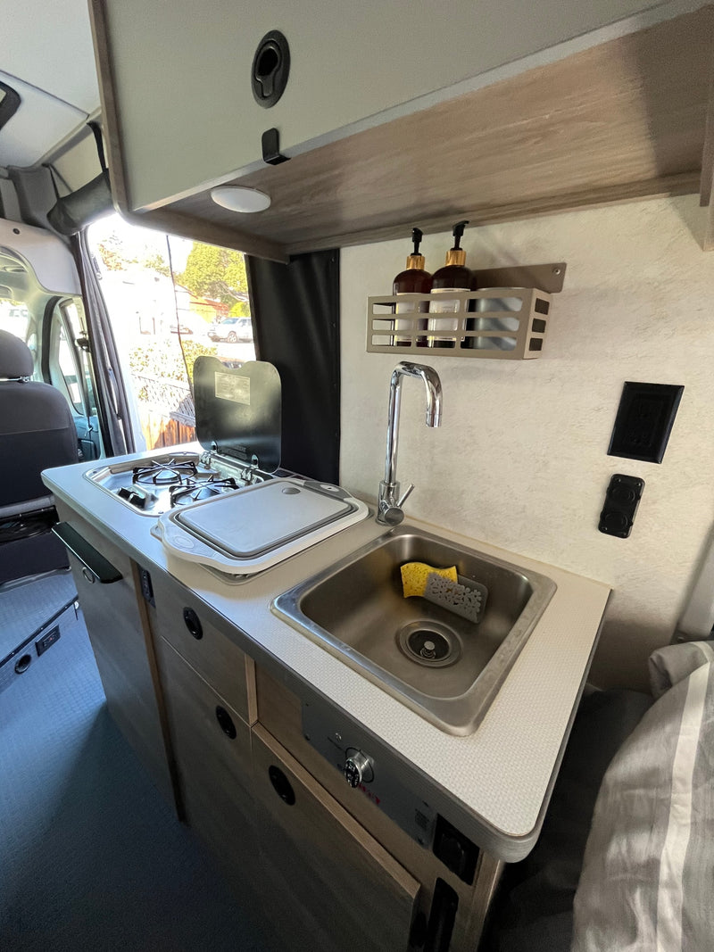 Well-appointed RV rental kitchen features a sink, stove, counter, and light wood cabinetry, ready for your road trip. — photo 13